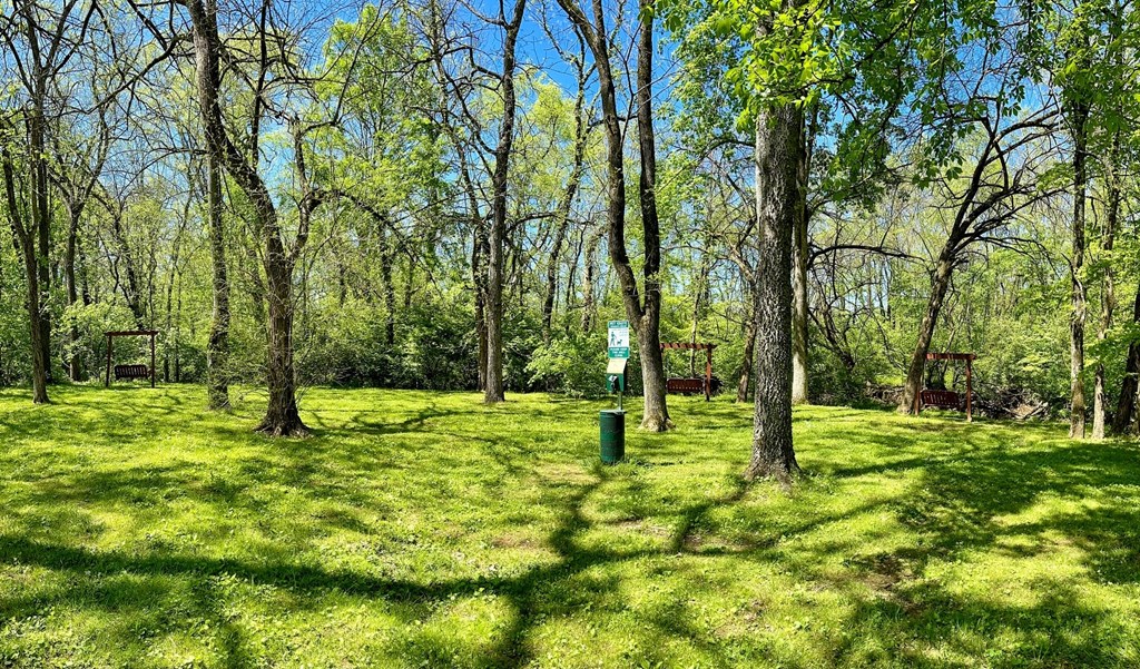Outdoor dog area at The Retreat at Indian Lake in Hendersonville exterior with pet waste station in the middle of grassy field with tall trees.