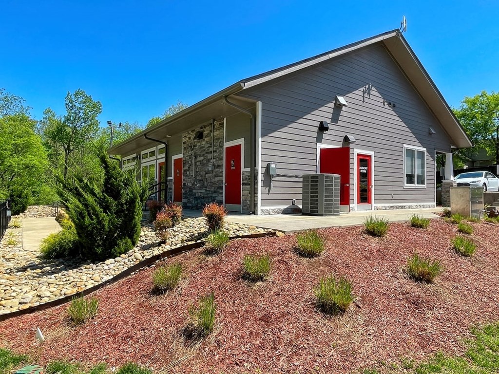 Main office of The Retreat at Indian Lake in Hendersonville exterior with grey siding, red doors, and meticulous landscaping.