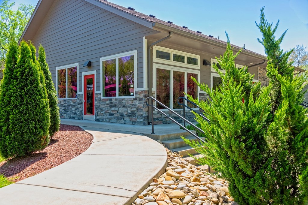 The Retreat at Indian Lake in Hendersonville community building exterior with grey siding, river rock wainscoting, and white trim windows.