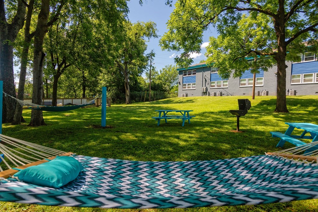 Blue and green chevron Hammocks in the community area at the Canvas Apartments in Nashville next to picnic tables and bbq shaded by large trees.