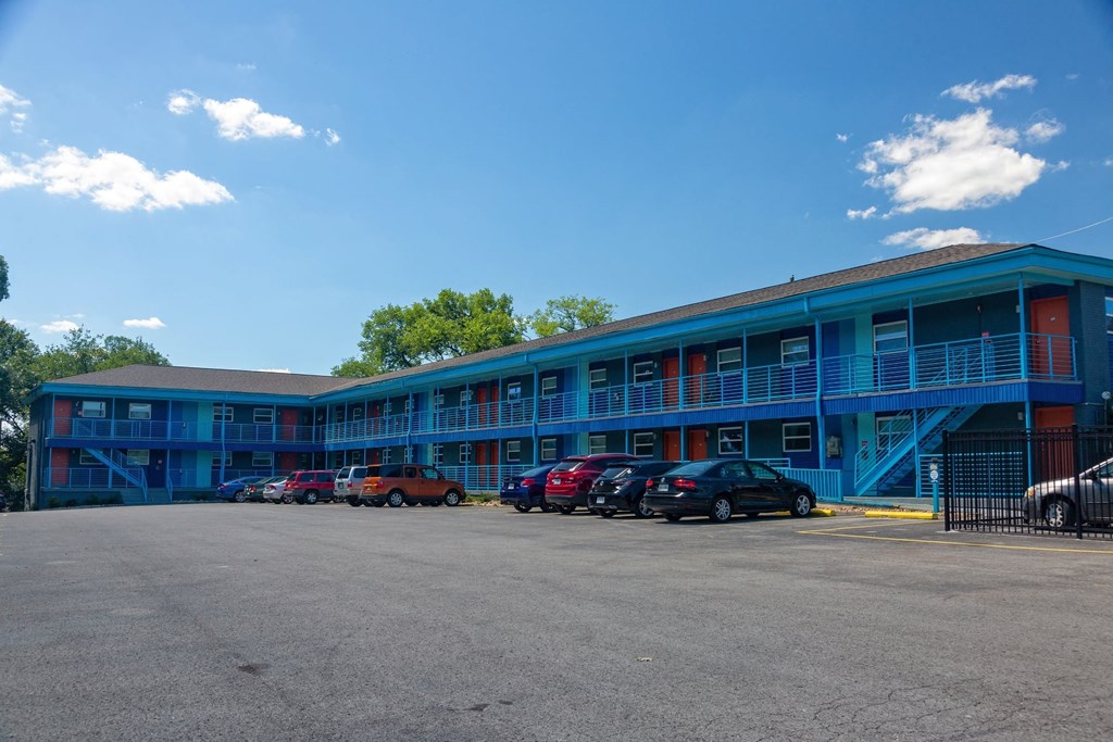 The Canvas apartments in Nashville, Tennessee. Building is two-story and has blue railings, red front doors, and private parking lot.
