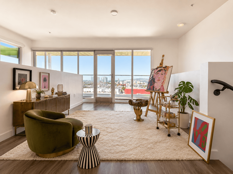 A living room with a green chair and a painting on the easel.