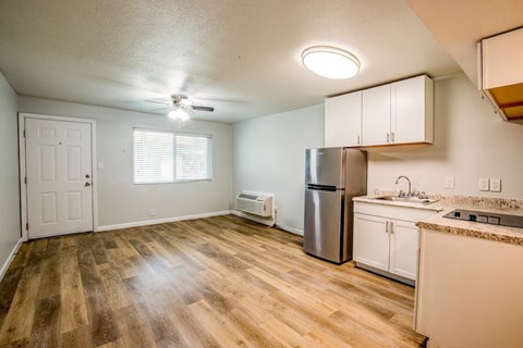 A kitchen with a refrigerator, sink, and cabinets.