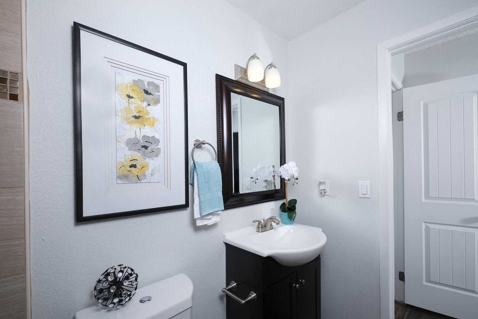 Bathroom in Fifteen 50 Apartments Las Vegas with floral art, vanity mirror, and sink with storage.