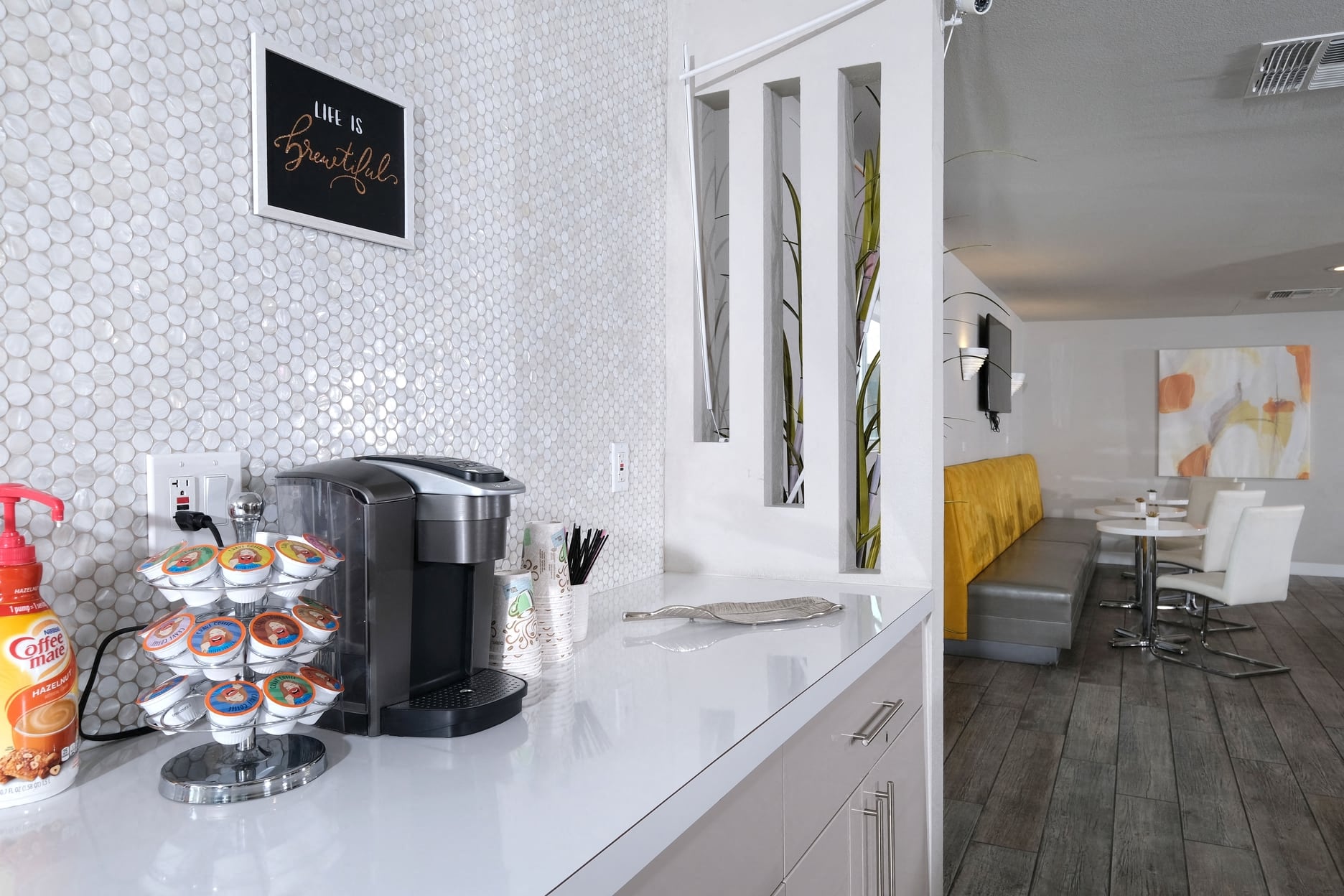 Fifteen 50 apartments Las Vegas clubhouse coffee corner with Keurig and coffee cups on counter with modern white penny tile backsplash.