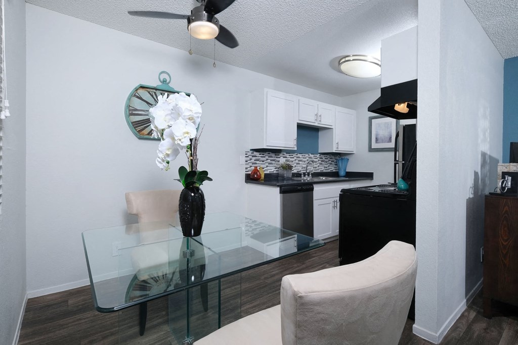Fifteen Fifty smoke free apartments Las Vegas open concept dining area and kitchen with white cabinets and modern glass dining table with white orchid