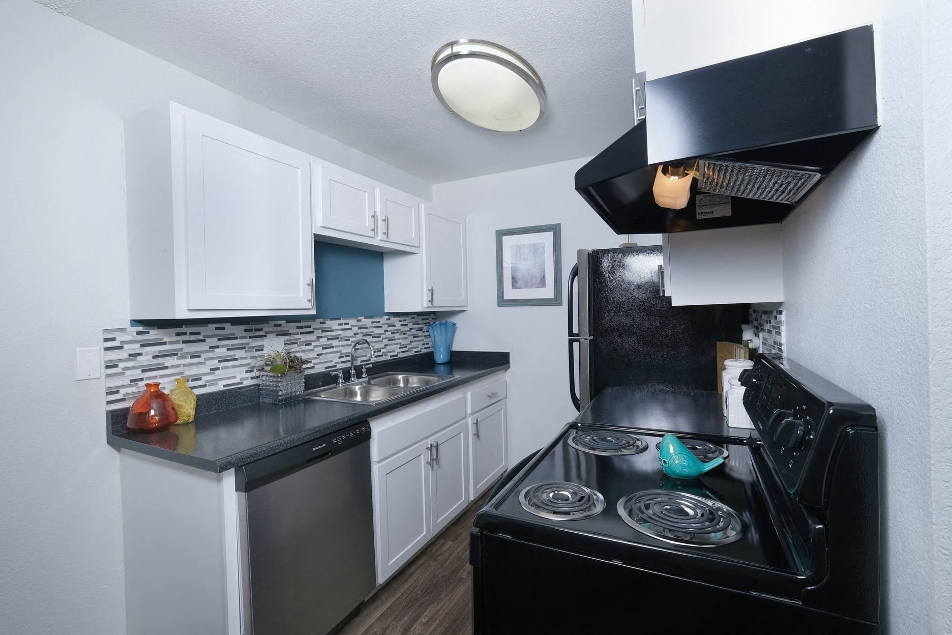 Fifteen 50 - Kitchen in Las Vegas apartment near strip with black and silver appliances, tile backsplash, and colorful modern vases on counters
