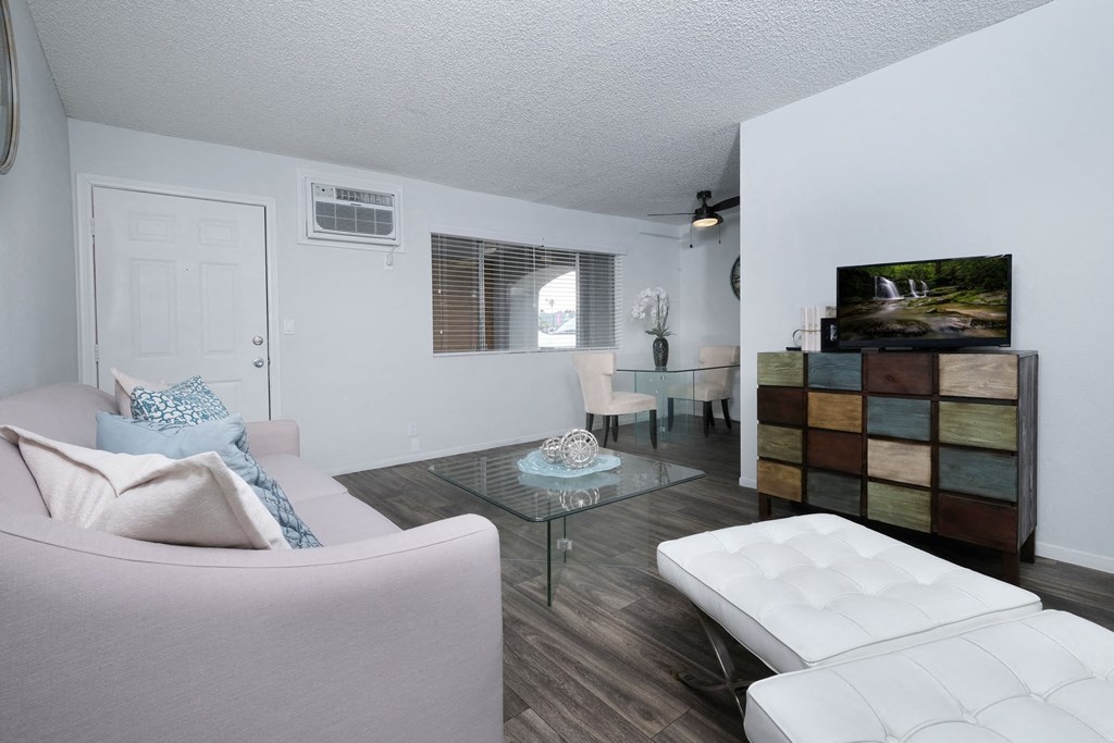 Fifteen 50 one bedroom apartments Las Vegas open concept living area with grey wood tile floors, modern stylish furniture, and large window