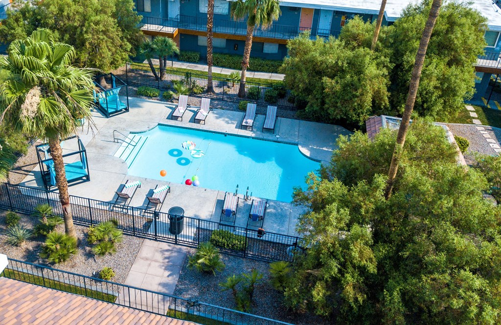 Aerial view of Fifteen 50 Apartments in Las Vegas with pool with blue cabanas, lounge chairs, and palm tree desert landscaping.