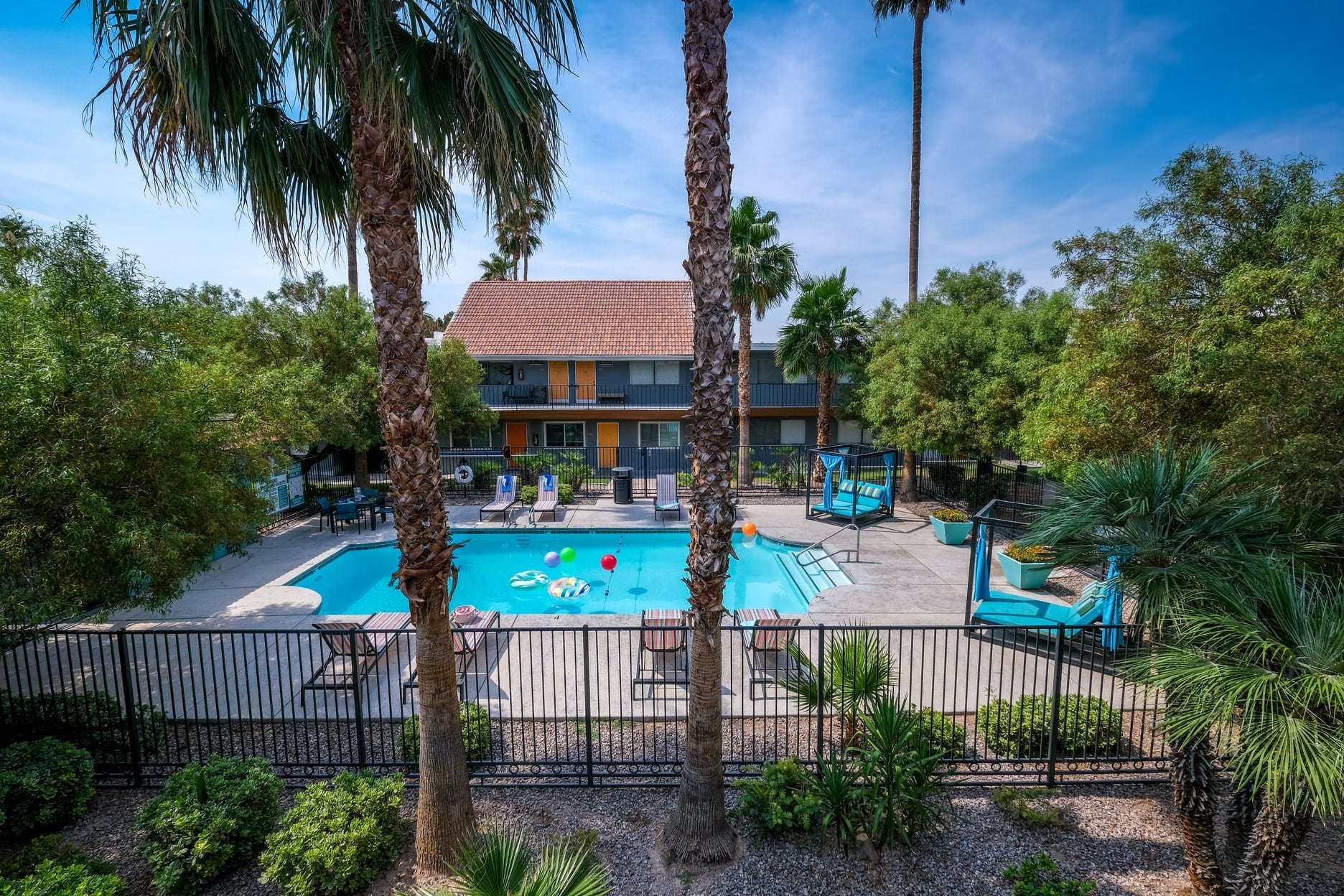 Aerial view of Community pool near Las Vegas strip and Fifteen 50 apartment buildings. Pool is surrounded by patio furniture and palm trees