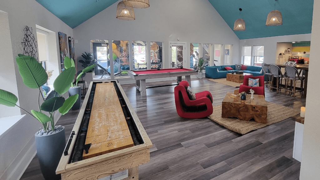 Fusion Orlando apartments clubhouse furnished with large seating area, pool table, shuffle board table, coffee corner, TV center, and gym.