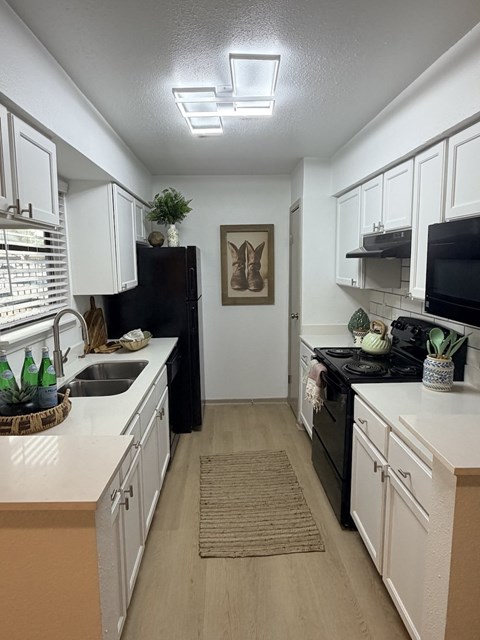 Fusion Crossroads kitchen with white cabinets and a black refrigerator.