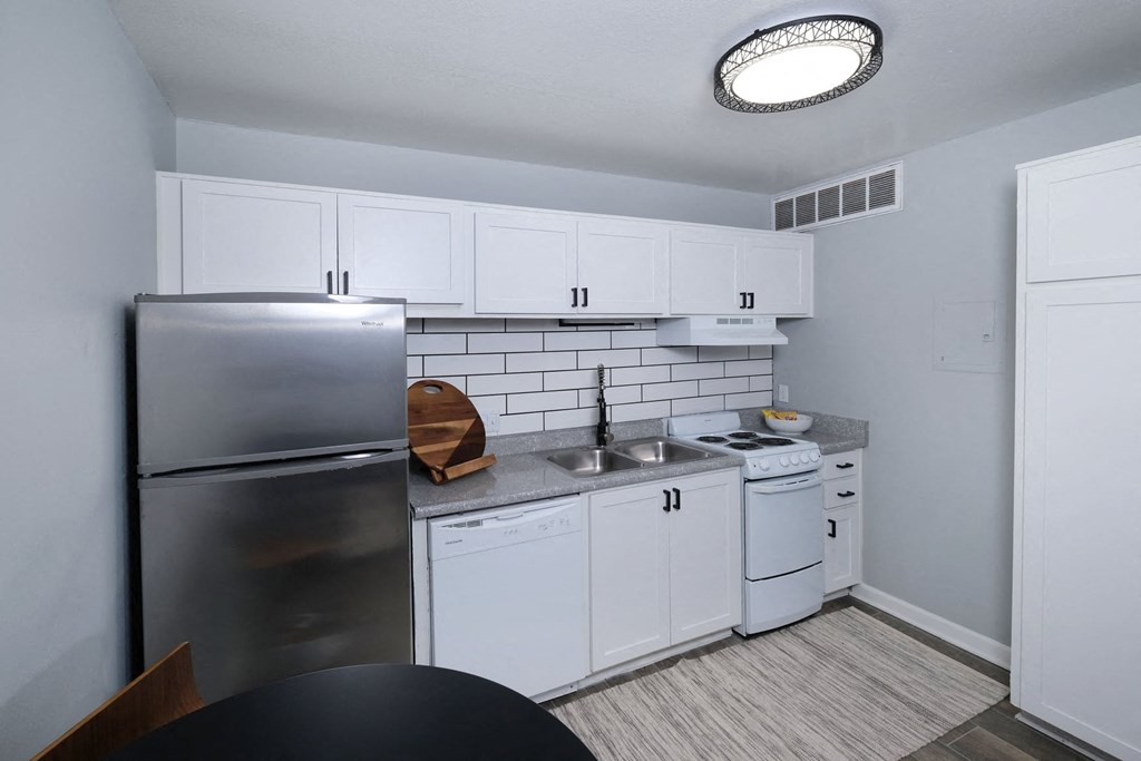 Fusion Fort Worth studio apartment in Haltom City kitchen with white dishwasher and stove, stainless steel refrigerator, and subway tile backsplash.