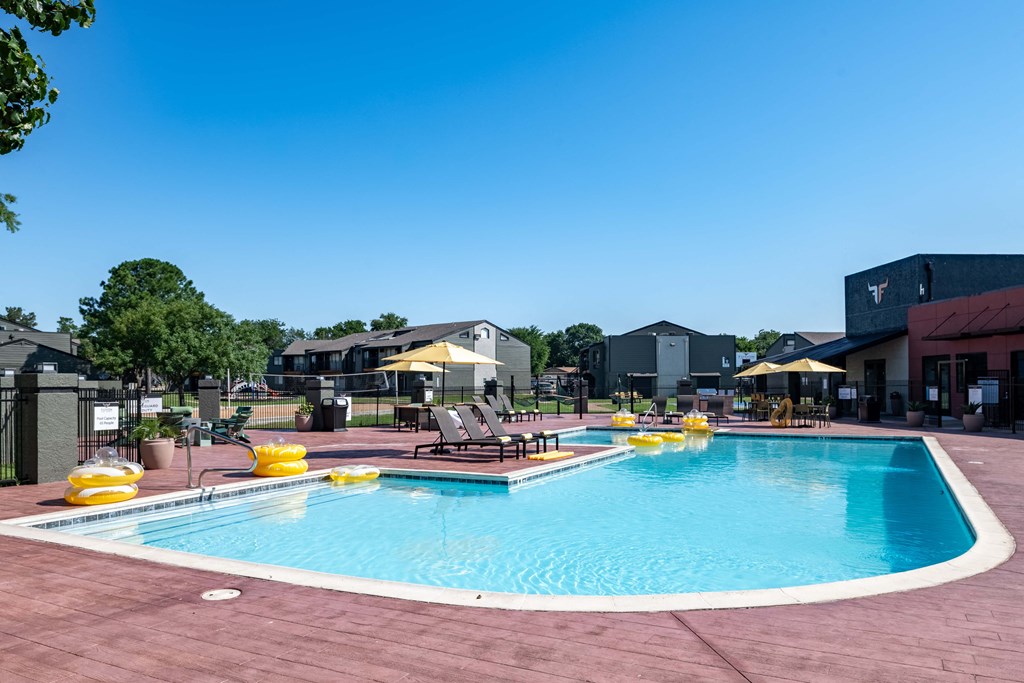 a resort style pool with lounge chairs and umbrellas in front of a building
