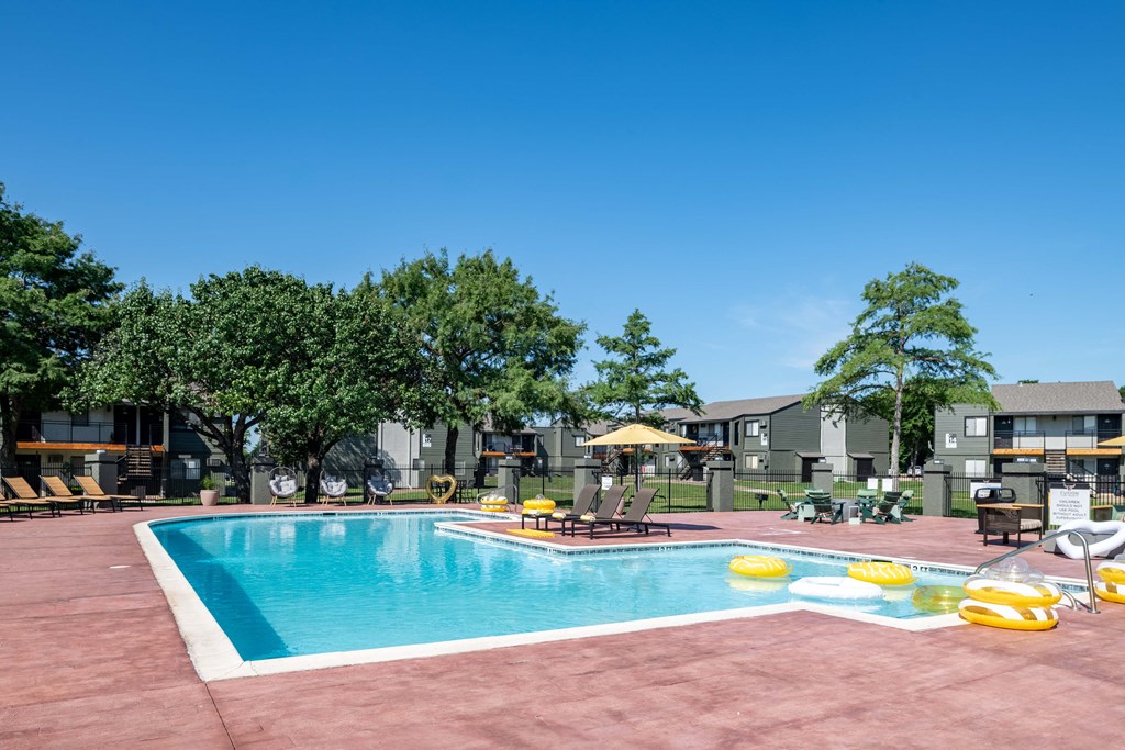 a swimming pool at an apartment complex with chairs and umbrellas
