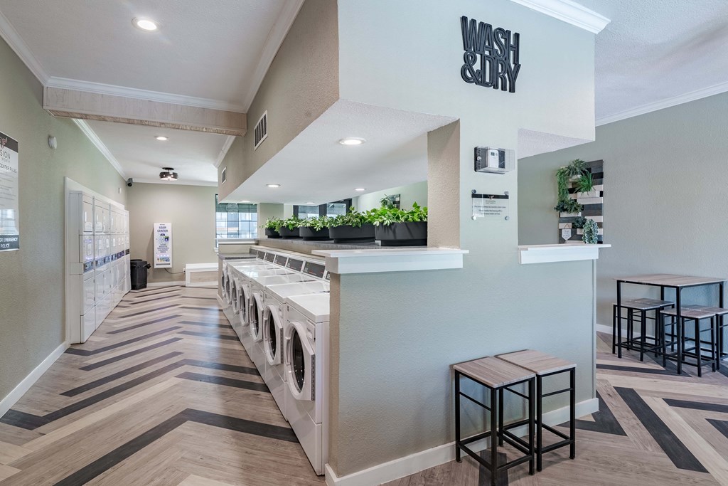 on-site laundry room in fusion Fort Worth apartments with herringbone flooring and large waiting area