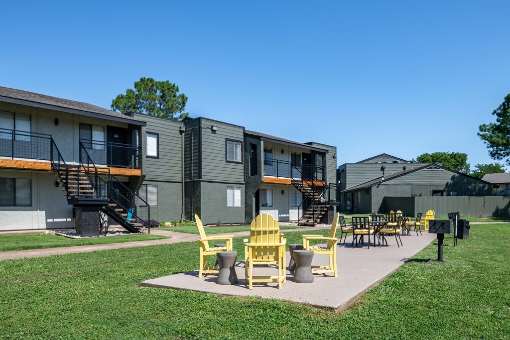 outdoor patio at fusion fort worth apartments with lawn, barbecue, and yellow patio furniture