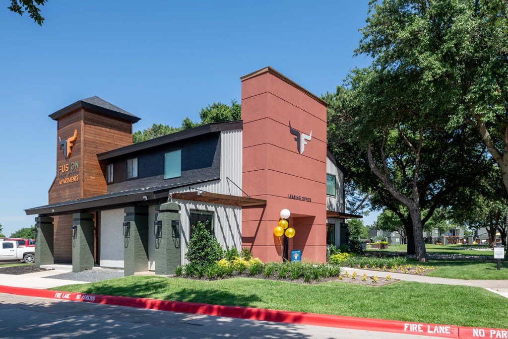 fusion Fort Worth leasing office with modern siding and awnings, green lawn, and large trees