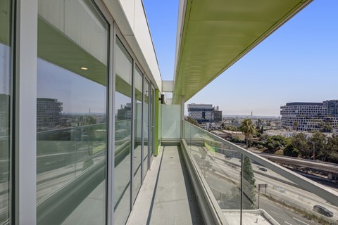 Fusion Hollywood private balcony with glass windows on the side and a view of the highway and buildings outside.