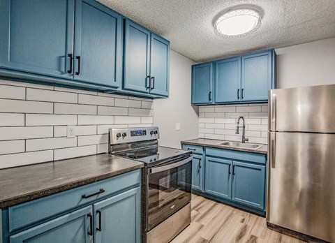 A kitchen with blue cabinets and a stainless steel refrigerator.