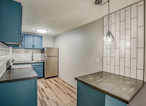 A kitchen with blue cabinets and a white tile backsplash.