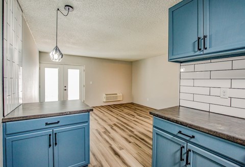 A kitchen with blue cabinets and a white tile backsplash.
