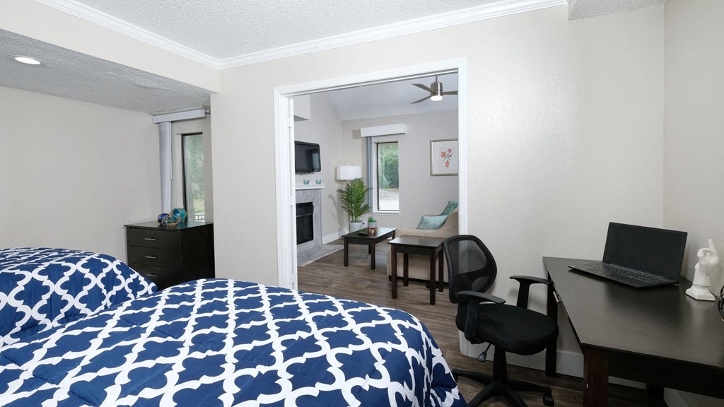 Fusion luxury apartments Orlando bedroom with two full beds, computer desk with chair, and espresso dresser in front of tall window.