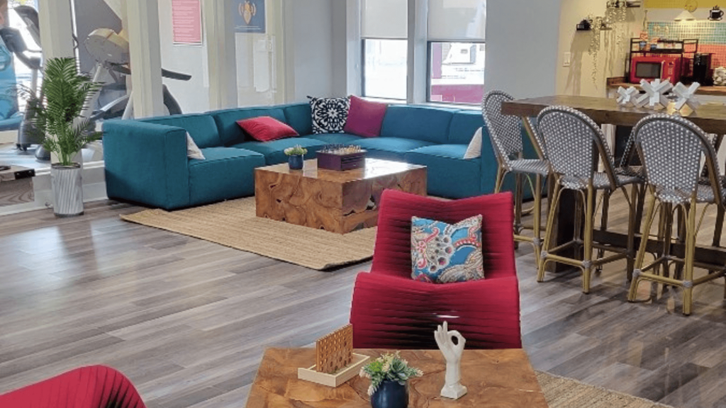 Fusion Orlando apartments clubhouse with large blue low-profile sectional and wooden block coffee table on a braided jute rug.