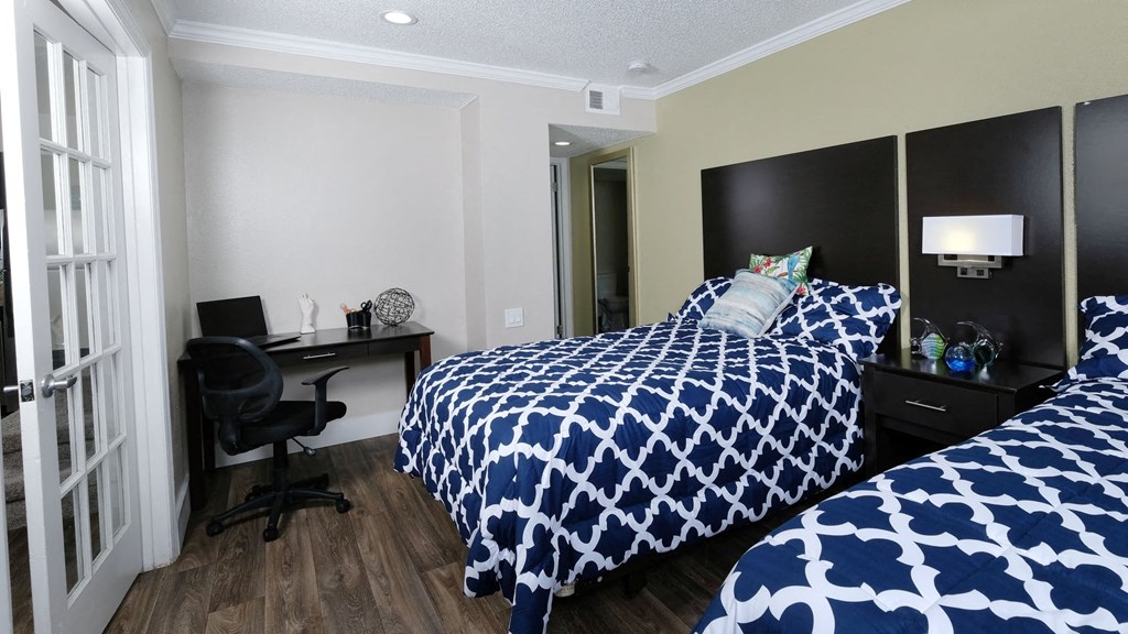 Fusion Orlando apartments Orlando, FL bedroom with two full beds with blue and white duvets, espresso headboards, and modern lamp and night stand between.
