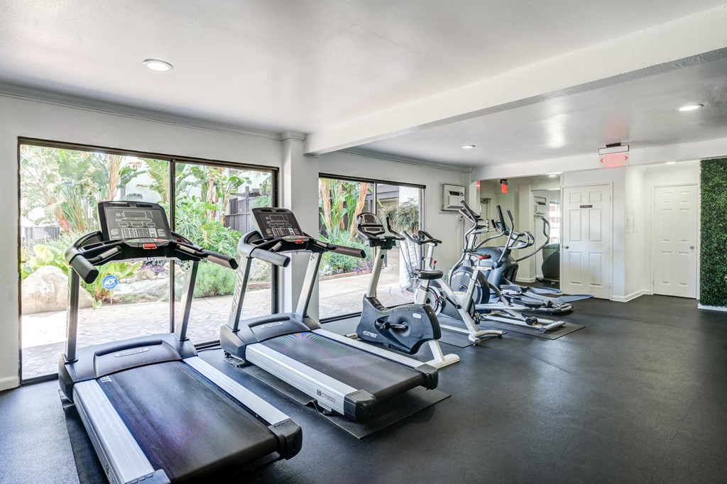 Fitness center in Fusion Warner Center apartments in Woodland Hills with cardio machines facing out large sliding glass windows.
