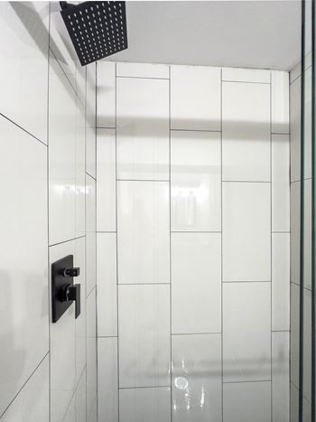A white tiled shower with a black shower head at the Retreat at Indian Lake Apartments in Hendersonville TN