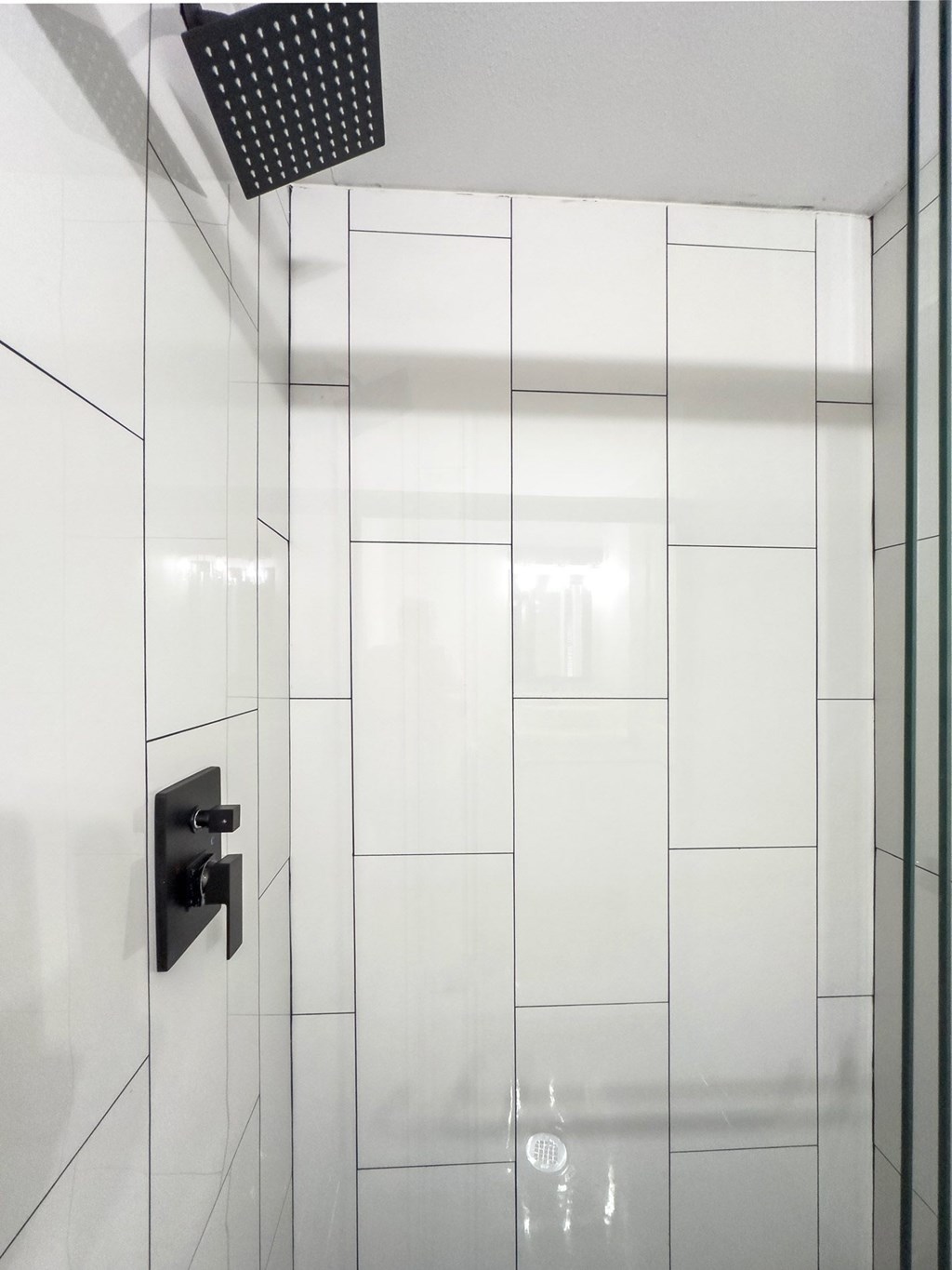 Retreat at Indian Lake apartments in Hendersonville, TN white tiled shower with a black shower head.