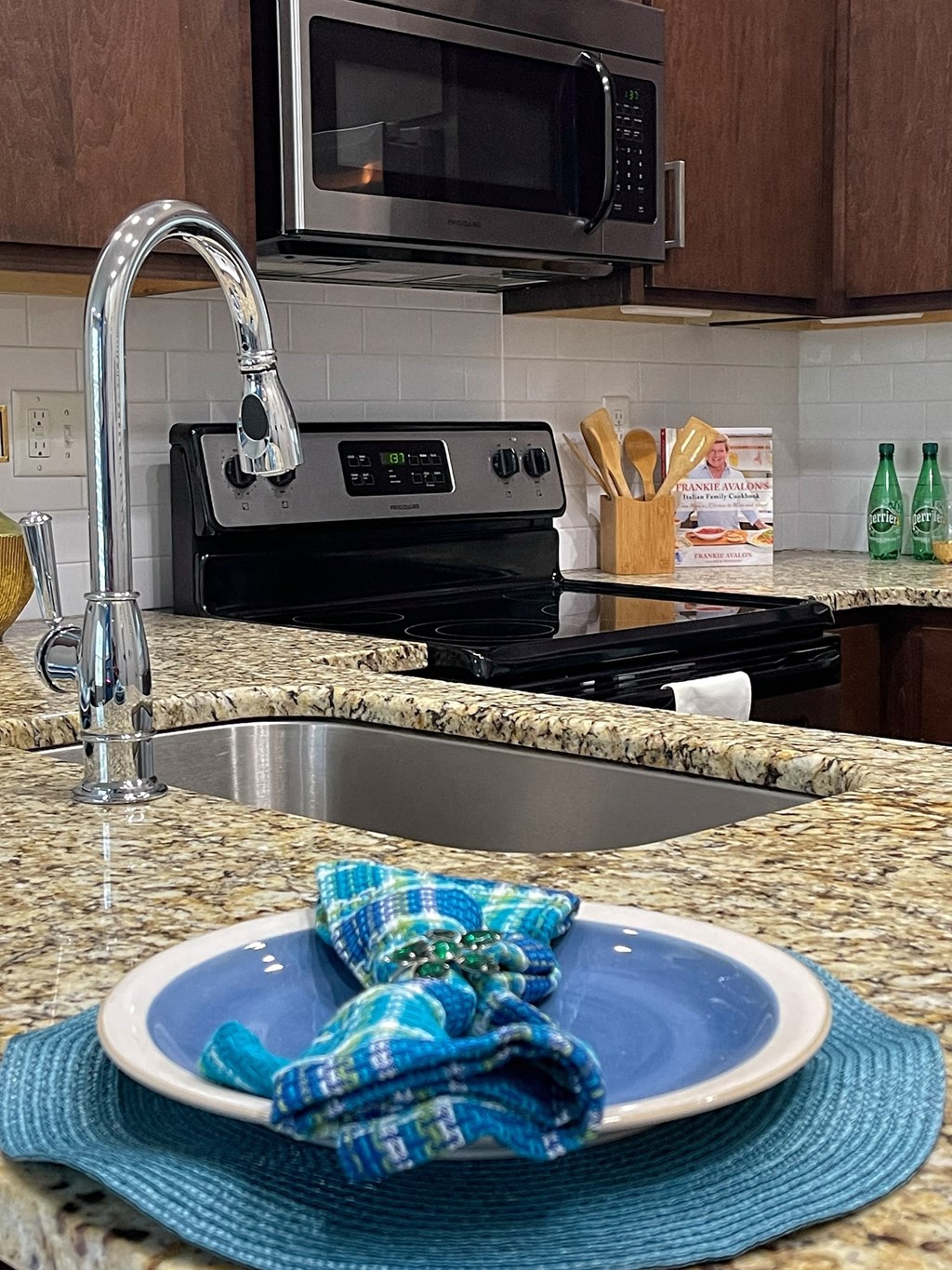 Kitchen in State Street Flats apartment in Nashville with large electric stove, microwave, and subway tile backsplash.