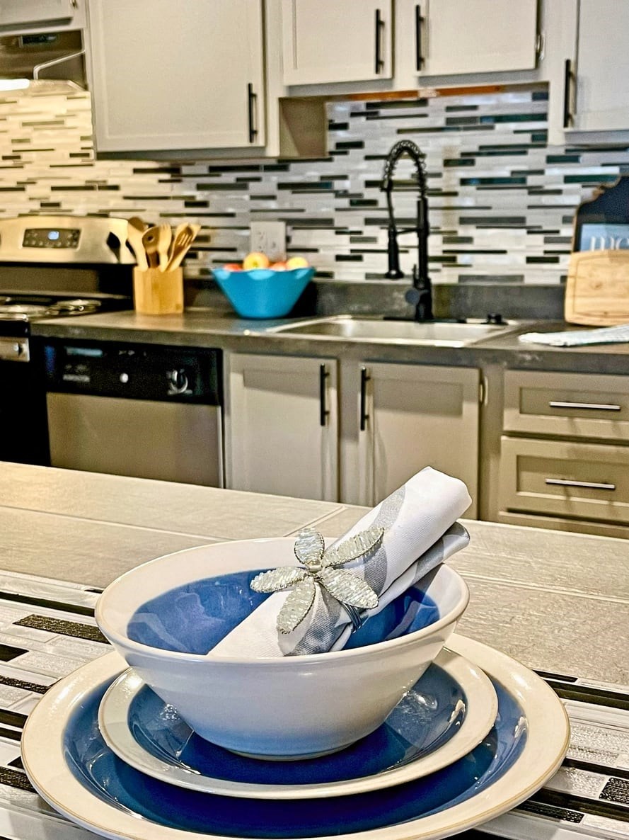 Place setting on kitchen island in the retreat at Indian Lake in Hendersonville with blue an cream plates and sliver napkin with beaded flower napkin ring.