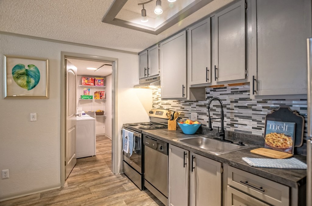 Kitchen in the Retreat at Indian Lake in Hendersonville with grey tile backsplash and door into large pantry with in-unit laundry.