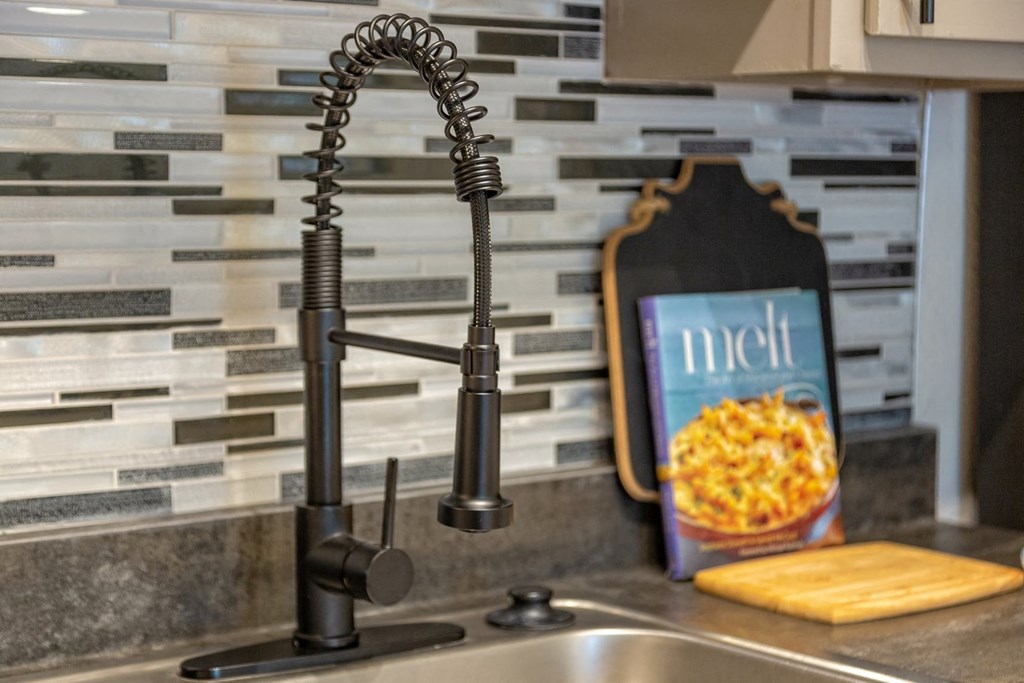 Kitchen sink in the Retreat at Indian Lake in Hendersonville with modern black matte faucet and greyscale tile backsplash.