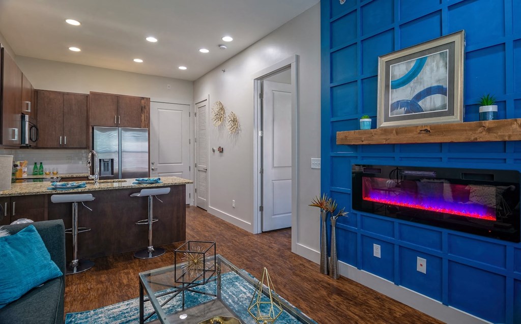 Open concept living area in one bedroom apartment in the State Street Flats in Nashville with blue accent wall and electric fireplace.