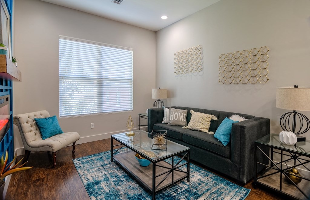 Living room in one bedroom apartment in the State Street Flats in Nashville with large window, modern decor, and luxury plank floors.