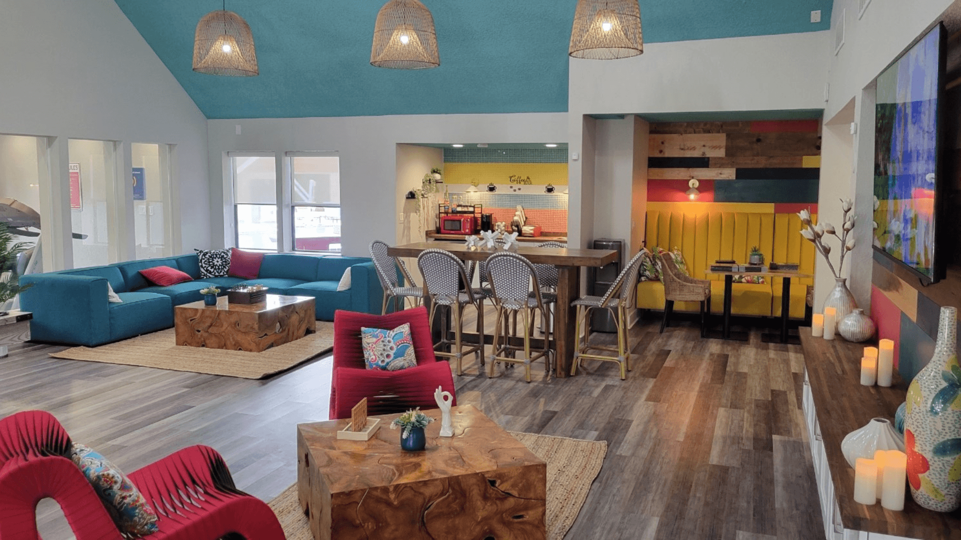 Fusion Orlando apartments lounge with colorful midcentury modern seating and decor, coffee center, and bar height table with wicker back chairs.