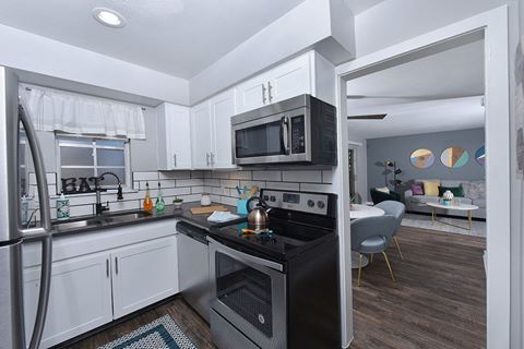 Lakeland, FL Apartments for Rent - Watermarc Apartments Kitchen with Stainless Appliances, Tile Backsplash, White Cabinetry, and Wood-Style Flooring