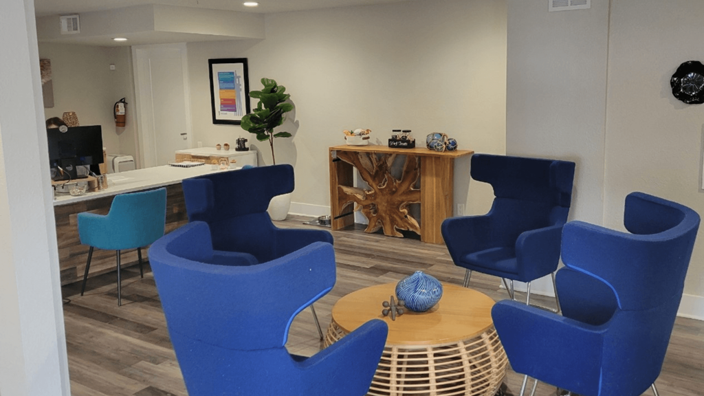 Fusion Orlando apartments reception desk and waiting area with four modern navy blue chairs around a round wooden coffee table.
