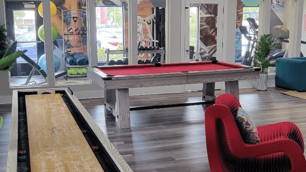 Fusion Orlando apartments clubhouse recreation amenities like tabletop shuffle board, pool table with red felt, and gym.