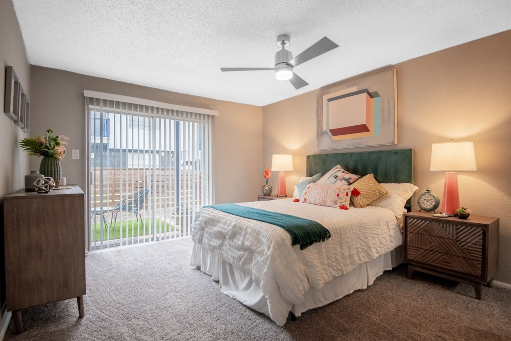 Large bedroom in Stadium 700 apartments in Arlington, TX with queen bed, ceiling fan, and large sliding glass door