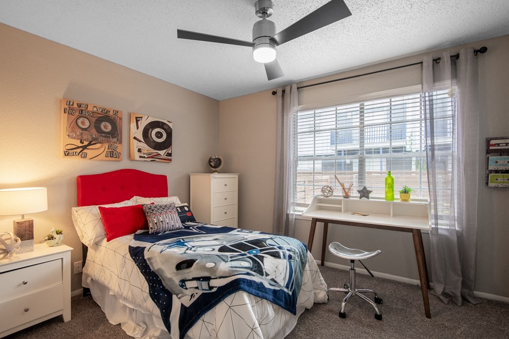 Bedroom in Stadium 700 2 bedroom apartments in Arlington, TX with large window, ceiling fan, and carpet