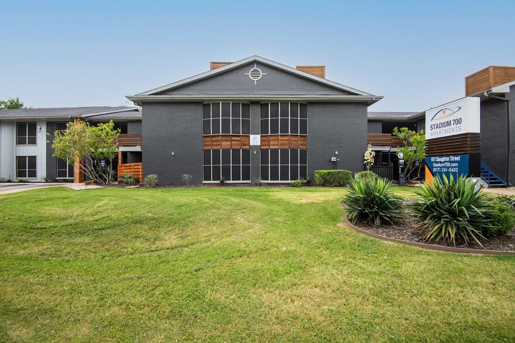 front of Stadium 700 apartments in Arlington, Texas with green lawn and grey walls.