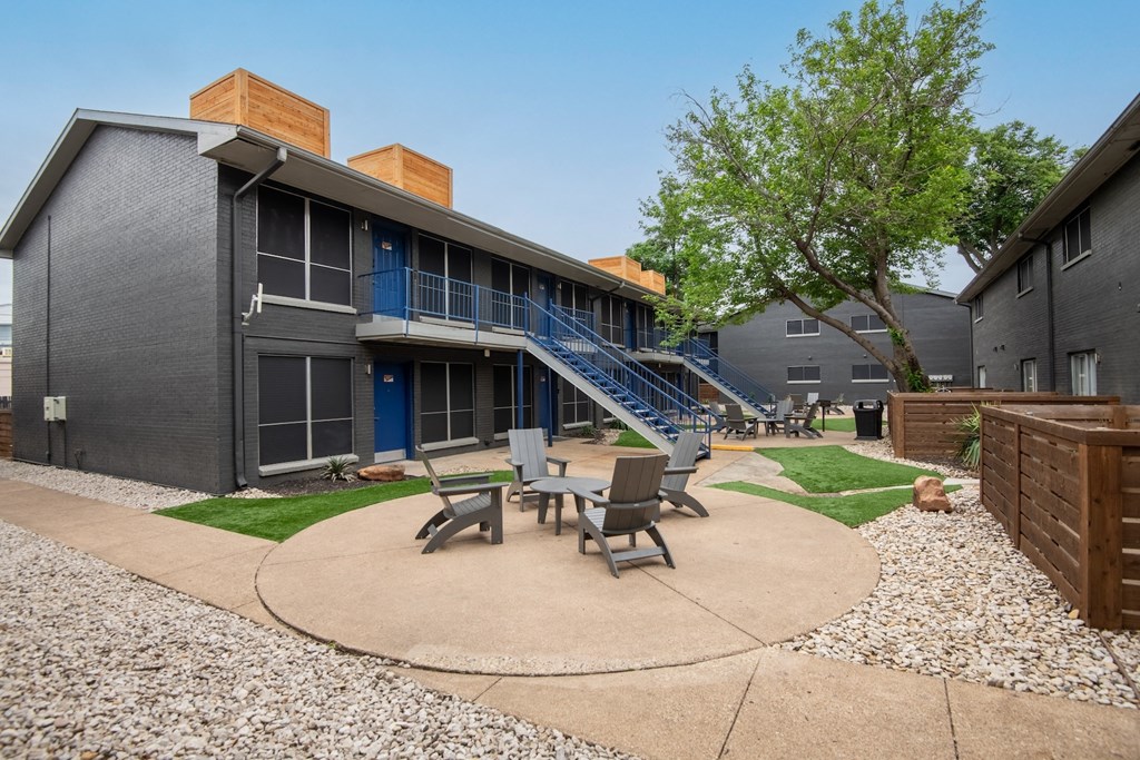 outdoor patio between apartment buildings at Stadium 700 in Arlington, TX with lawn chairs and table.