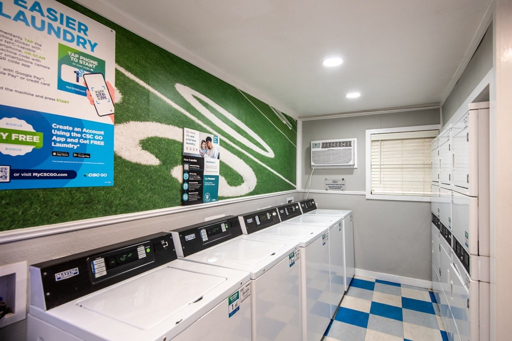 Community laundry room at Stadium 700 apartments in Arlington, TX with tile floors and many washers and dryers