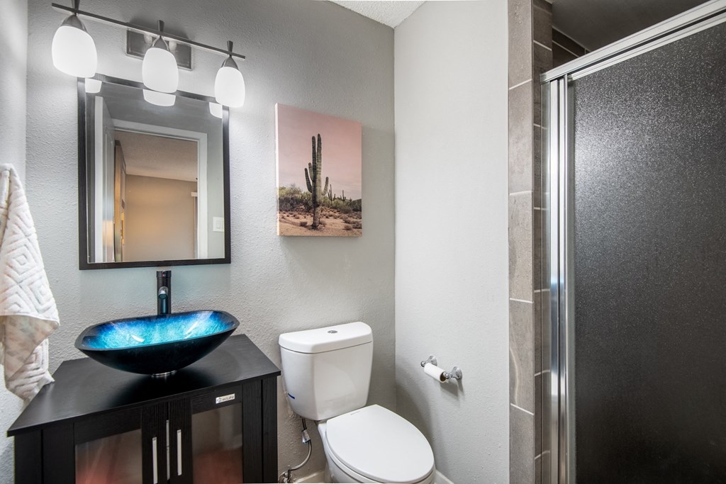 Modern bathroom in Stadium 700 apartments with a basin sink, toilet, and shower with frosted glass door.