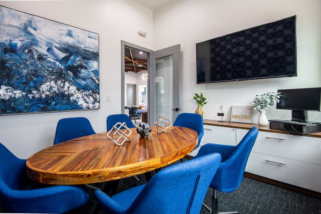 Conference room at stadium 700 apartments in Arlington, TX with large flat screen tv, oval conference table, and storage furniture