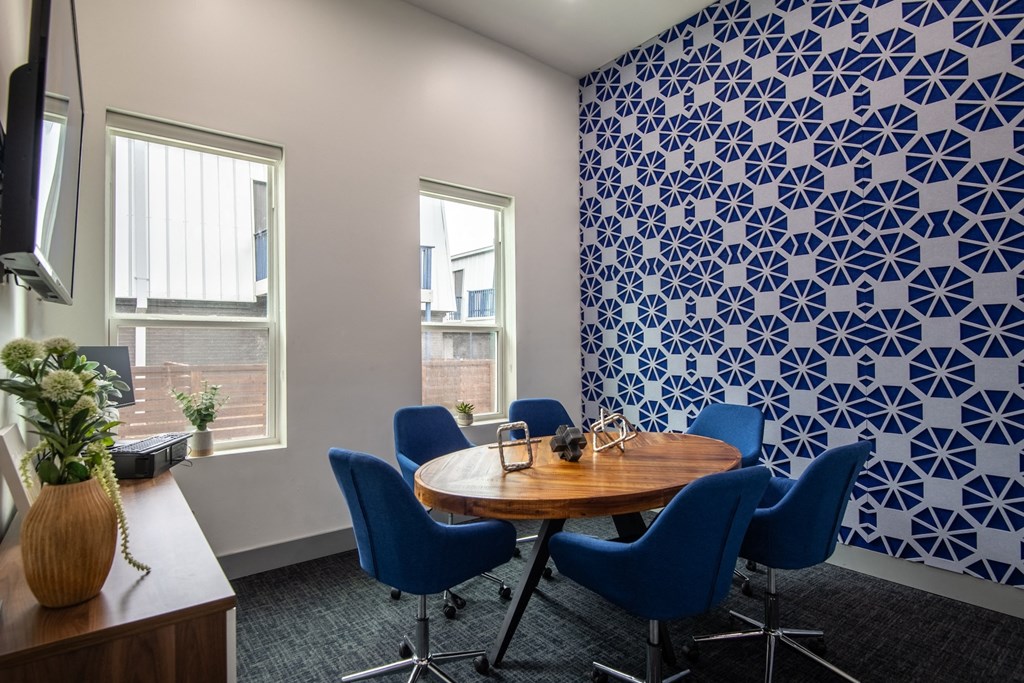 Conference room in Stadium 700 Apartments in Arlington, TX with round wooden tables and blue velvet chairs